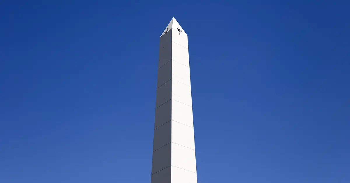 A white stone obelisk set against a blue sky