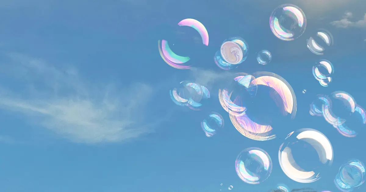 A cluster of bubbles in a near-clear blue sky with a wispy cloud