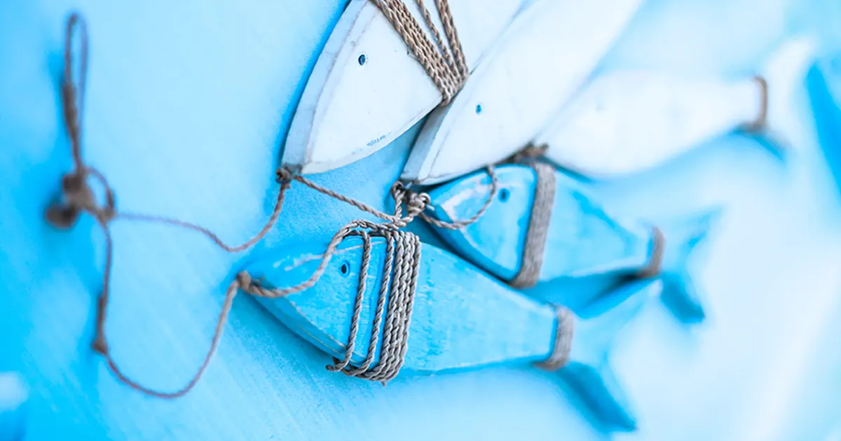 Carved, wooden fish painted blue and tied together on a line.