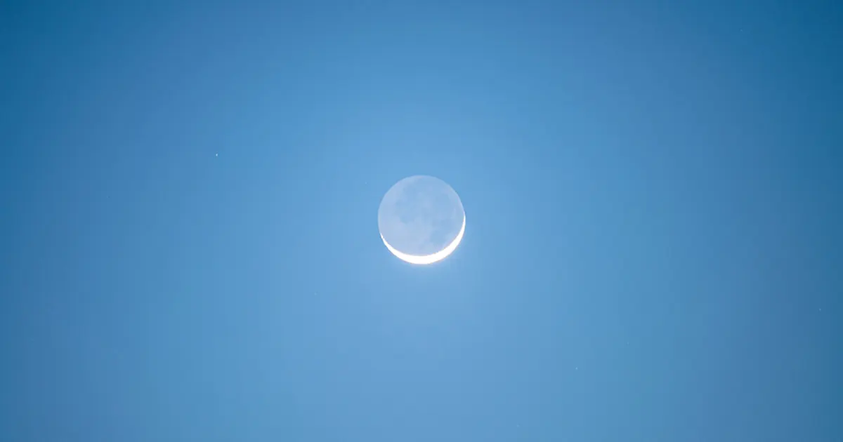 Near total solar eclipse in a twilight blue sky